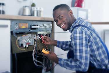 Smiling appliance technician working on oven