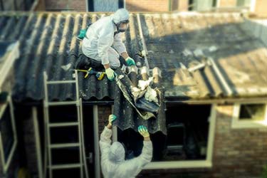Two workers in the process of removing asbestos from roof