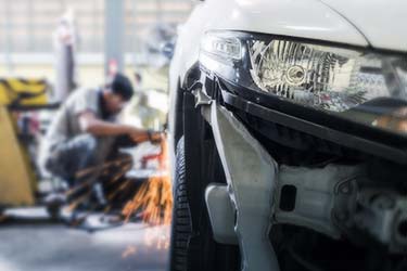 Close up of car headlight with auto body repair specialist in background