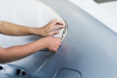 Protective tape being applied to car window prior to painting