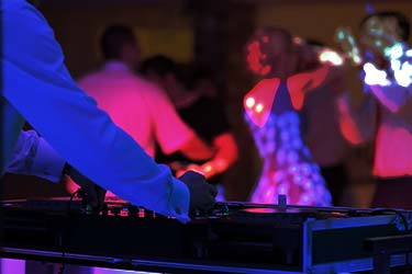 Colorful shot of DJ playing music to guests on a dancefloor