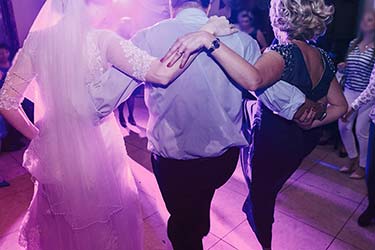 Family of the bride dance with guests to music played by DJ at wedding