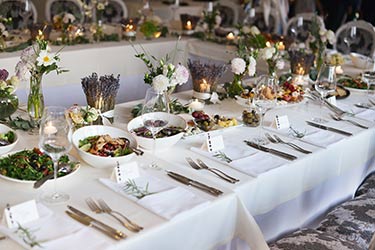 Table settings for catered dinner, framed by charming fresh floral arrangements