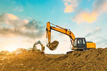 Multiple excavators work to clear earth on job site