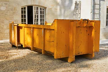 Large yellow metal dumpster on job site, ready to collect rubbish and debris during construction job