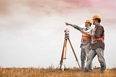 Two land surveyors discussing site and surveying land with tools