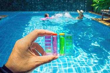 Pool cleaner holding pool water chemical test, showing results for pH levels, chlorine, and more