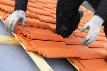 Close up of roofer installing terracotta roofing tiles