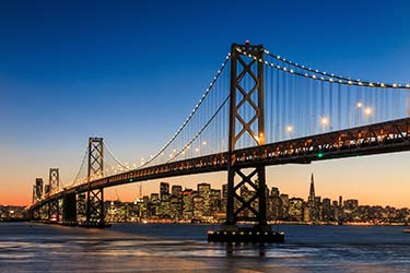 The glorious Golden Gate Bridge lit up at night with the San Francisco city skyline in the background