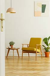 Professionally upholstered retro occasional chair in mustard colored cloth on wooden floor in light and modern living space