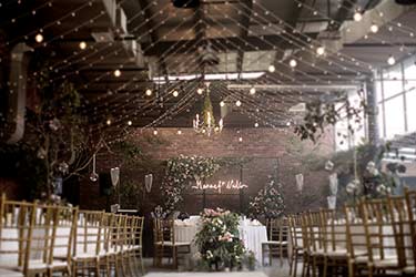 Rustic barn wedding with string lights and neon sign with couple’s name