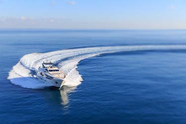 Aerial shot of luxury yacht turning at speed on ocean